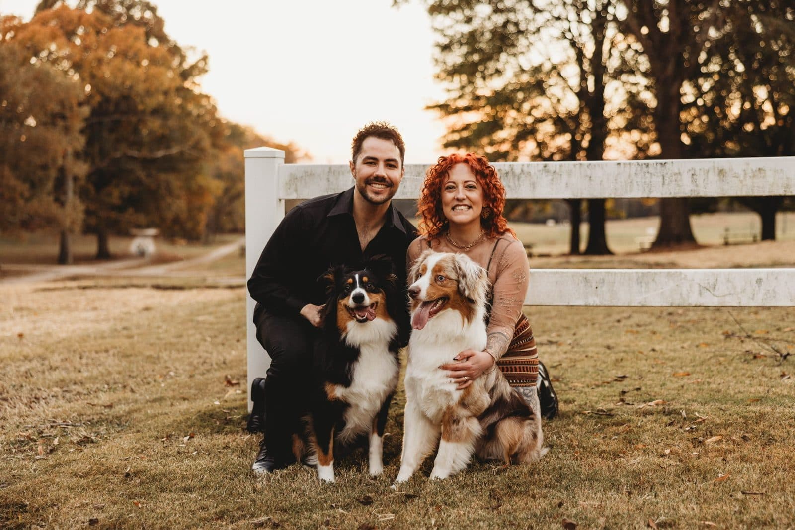 Nikki and her husband kneeling in a park at sunset with Zuko and Wanda, their two Australian Shepherds